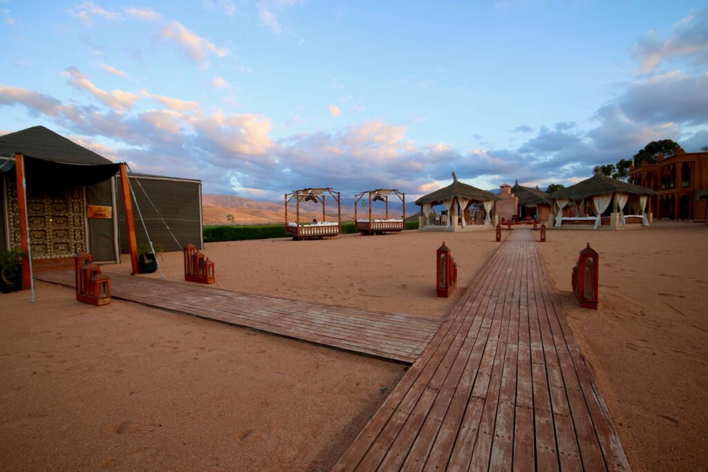 Agafay vs Sahara - A wooden boardwalk leads through a luxury desert camp in Agafay