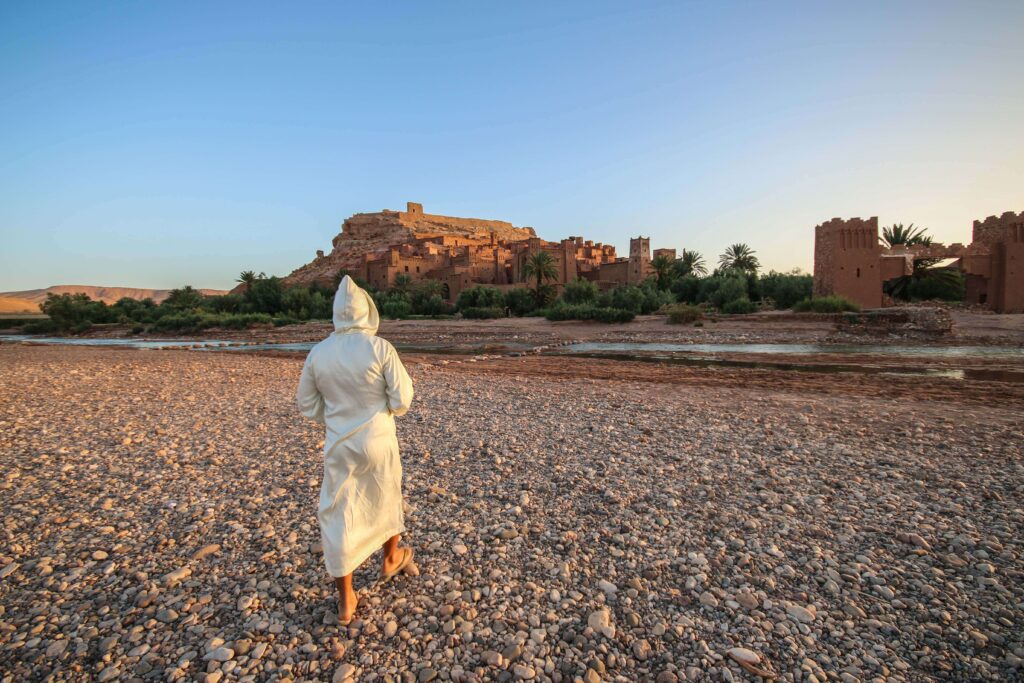 A Moroccan man wearing a djellaba walking through Ait Benhaddou