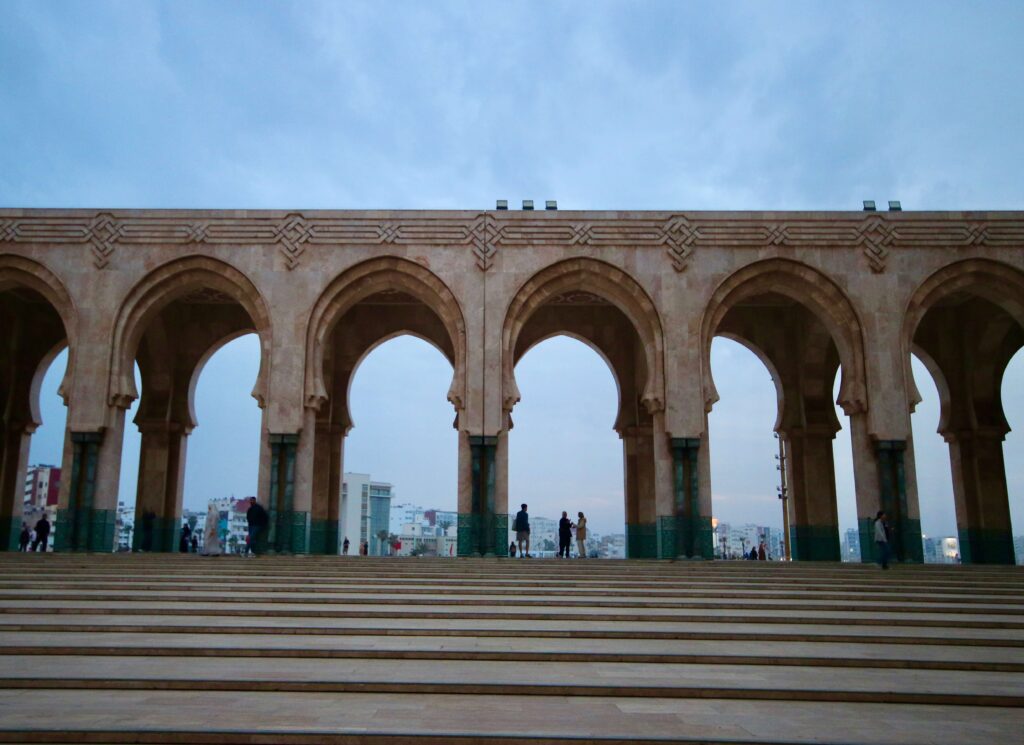 People gather beneath the arches of the Hassan II Mosque in Casablanca, Morocco