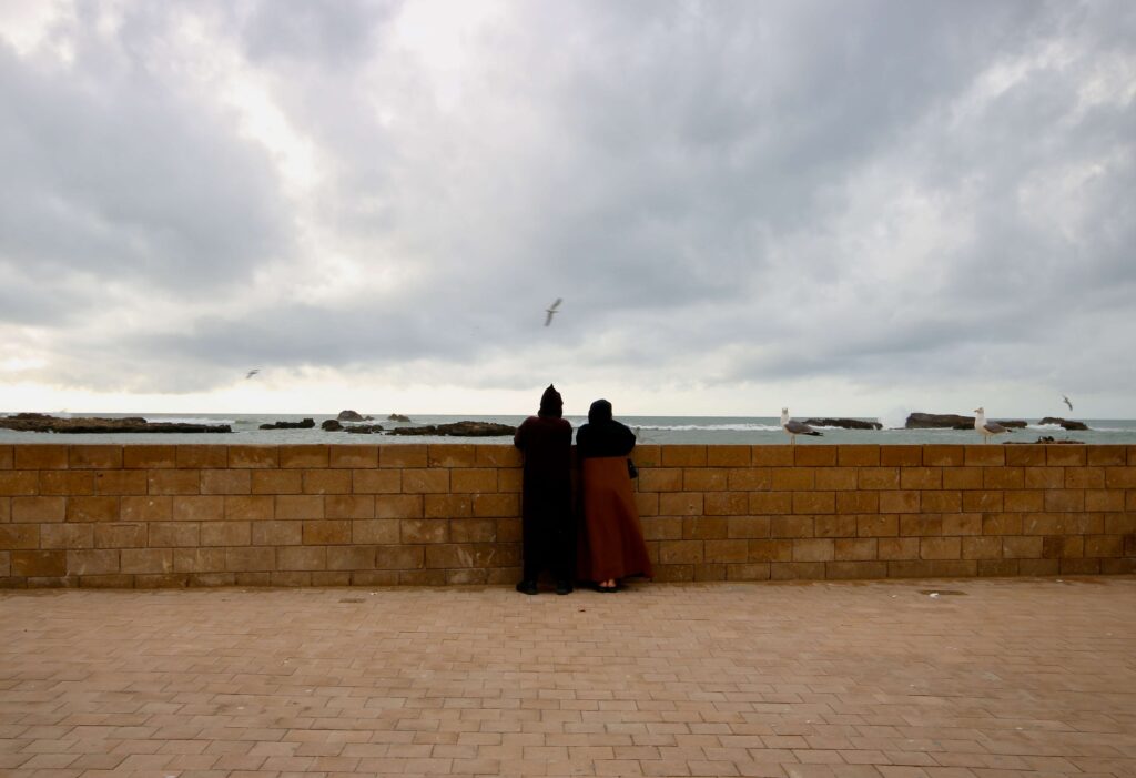 A Moroccan couple looking out across the Atlantic Ocean at the Essaouira port