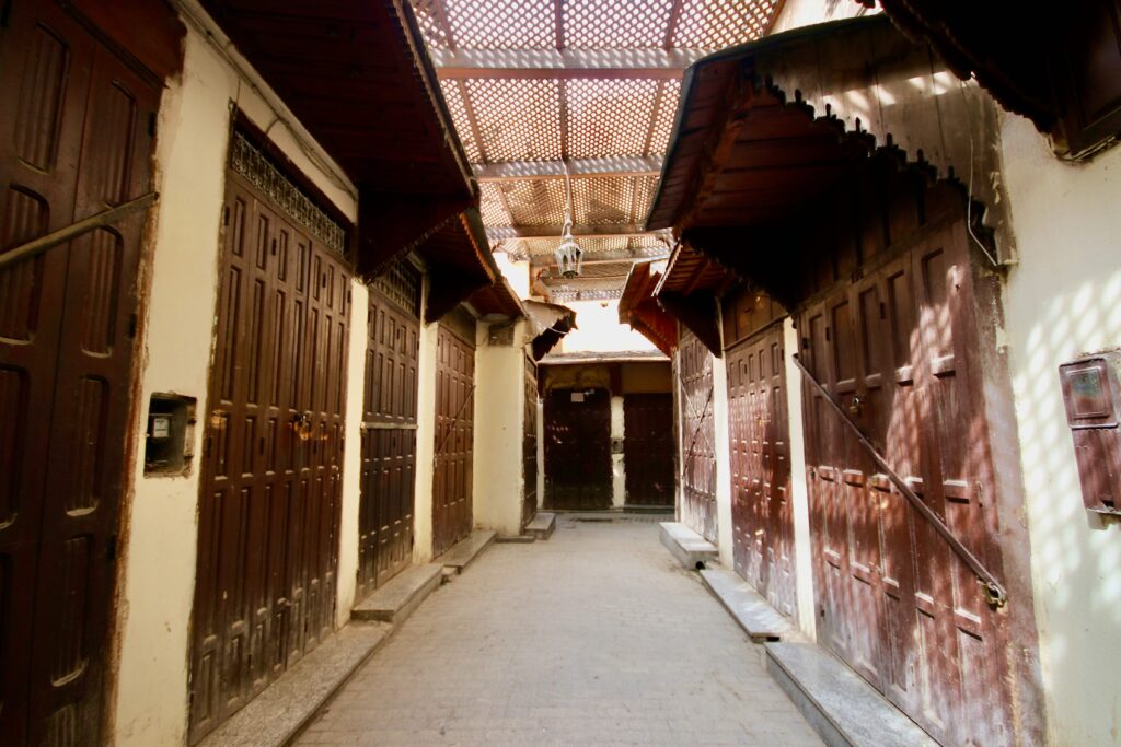 Closed shopfronts line a narrow street in the Fes medina