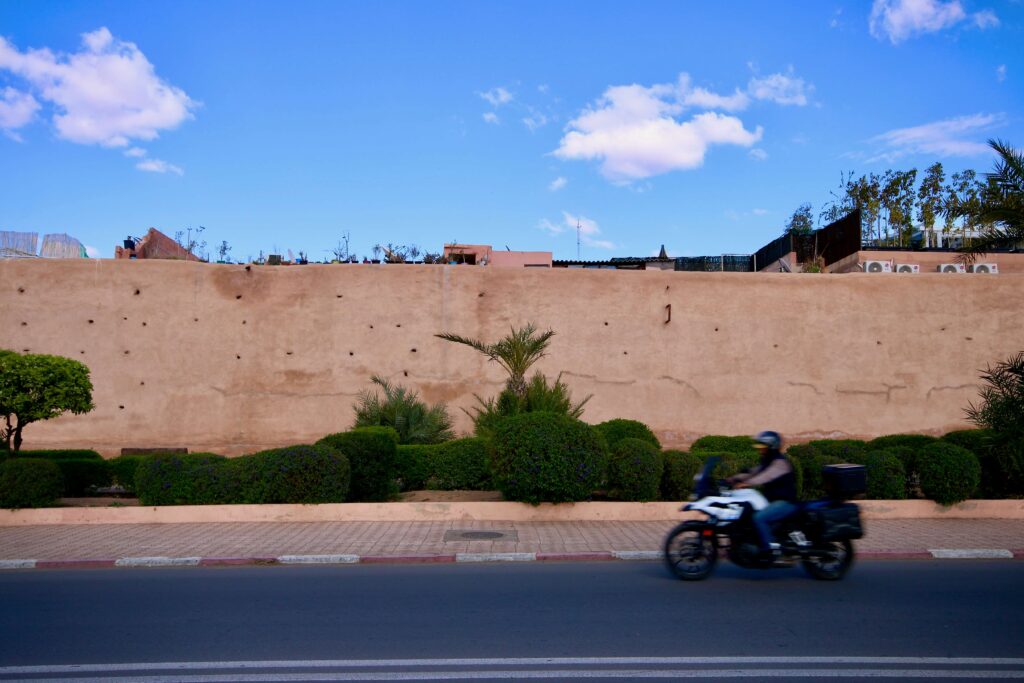 Visiting Marrakech in December - A motorbike drives along the ochre walls of the Marrakech medina