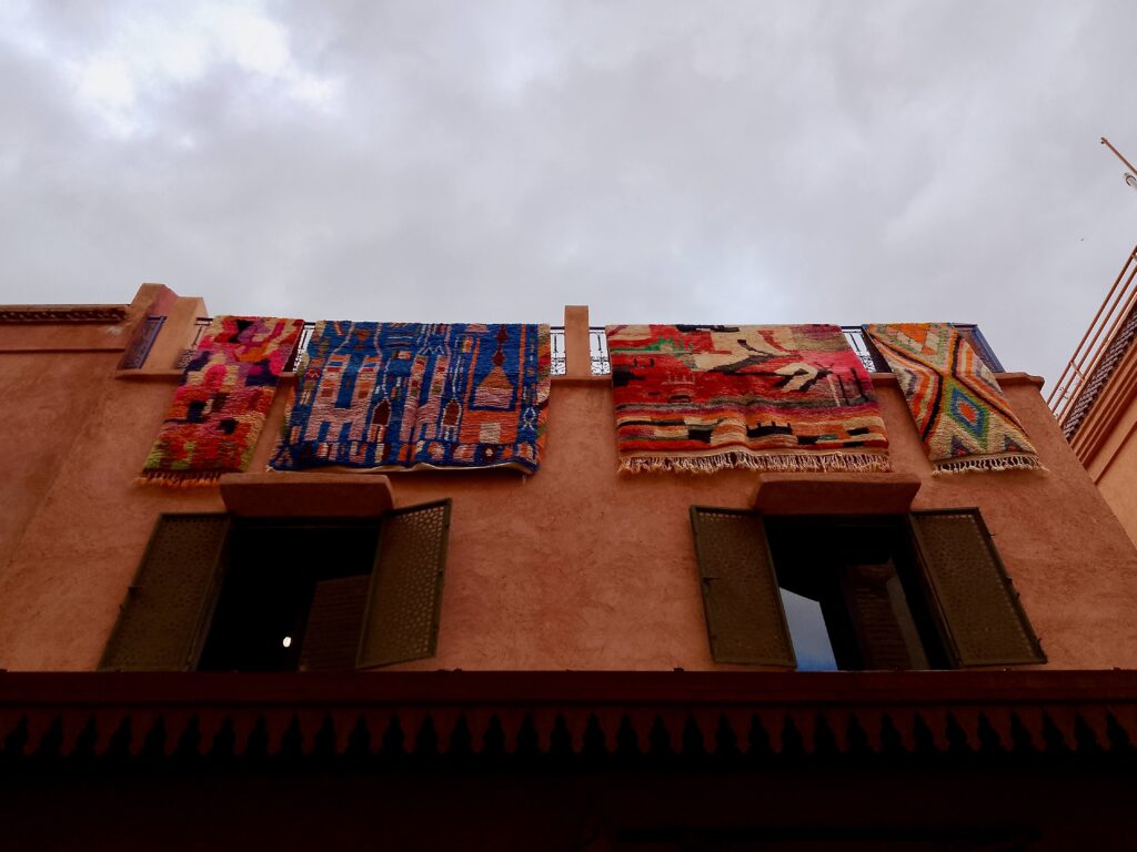 Colourful rugs hanging over a terrace balcony in the Marrakech medina