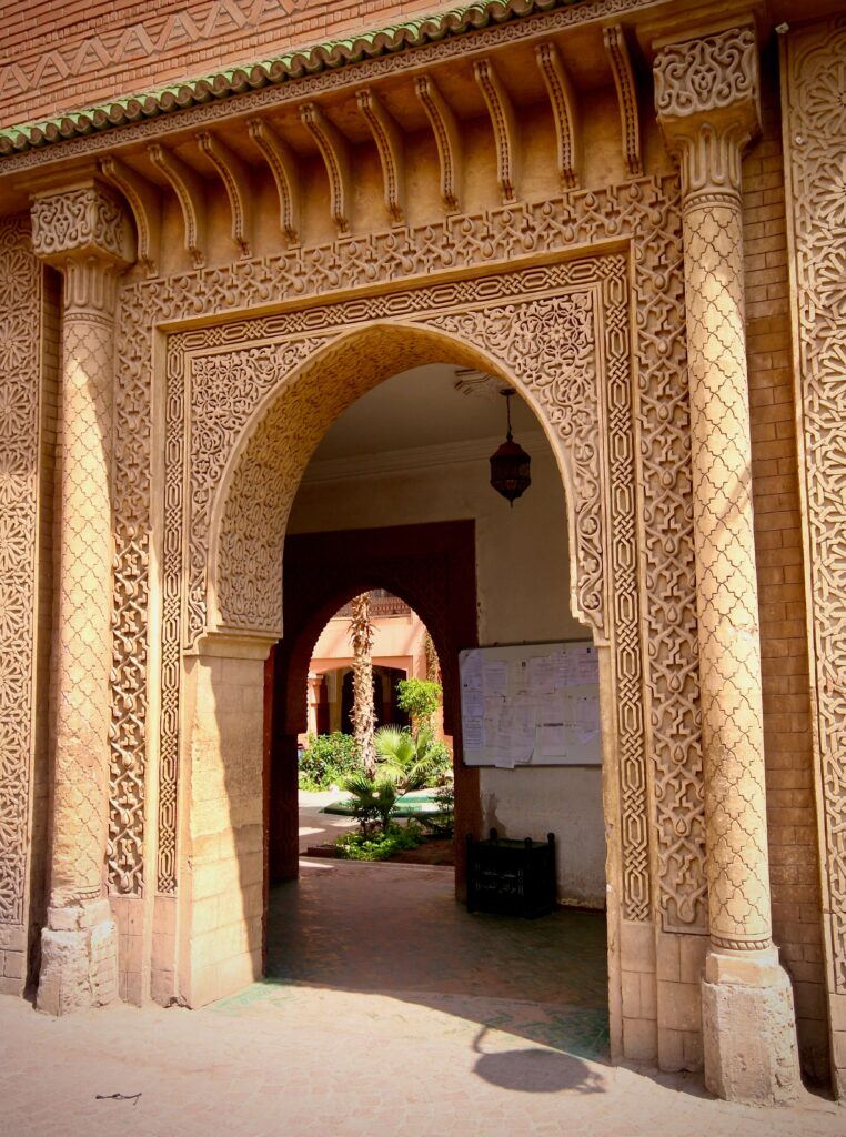 Looking through an ornately decorated archway into a leafy courtyard in the Marrakech medina