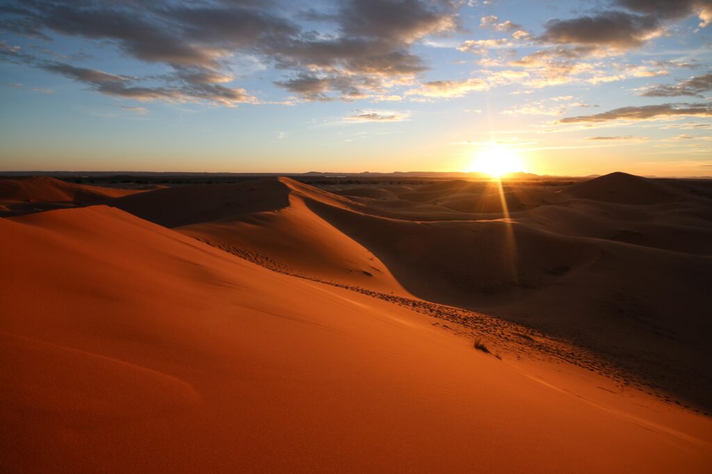 Best things to do in Merzouga - Sunrise illuminates the dunes of the Sahara Desert an ochre red colour