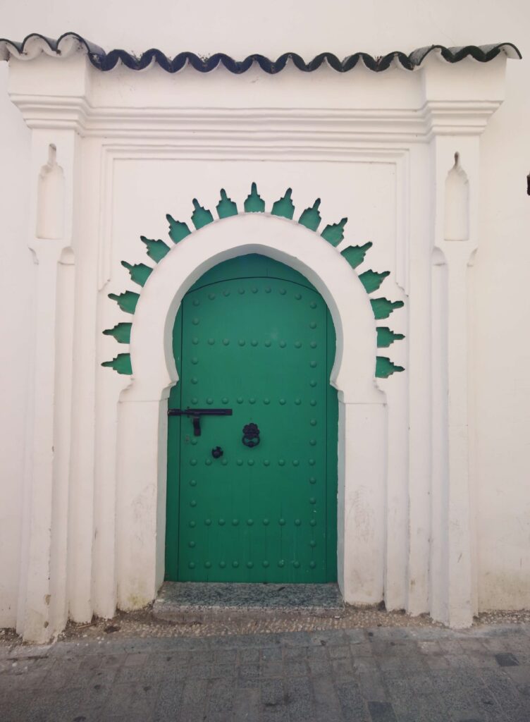An arched green door on a whitewashed building in the Tangier medina