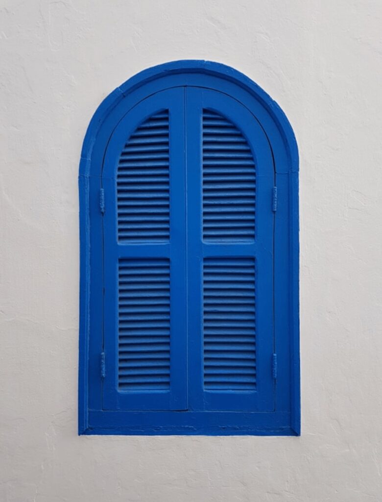 Travel guide to Asilah - An arched blue shutter window on a whitewashed building in Asilah, Morocco