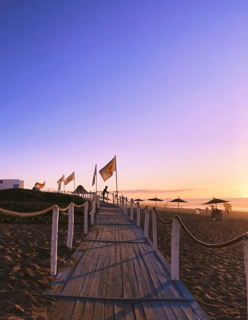 Travel guide to El Jadida: Flags fly above a beach boardwalk in El Jadida, Morocco
