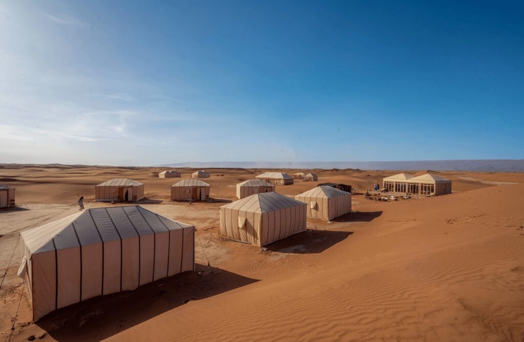 Tents nestle at the base of a dune in Erg Chigaga, Morocco