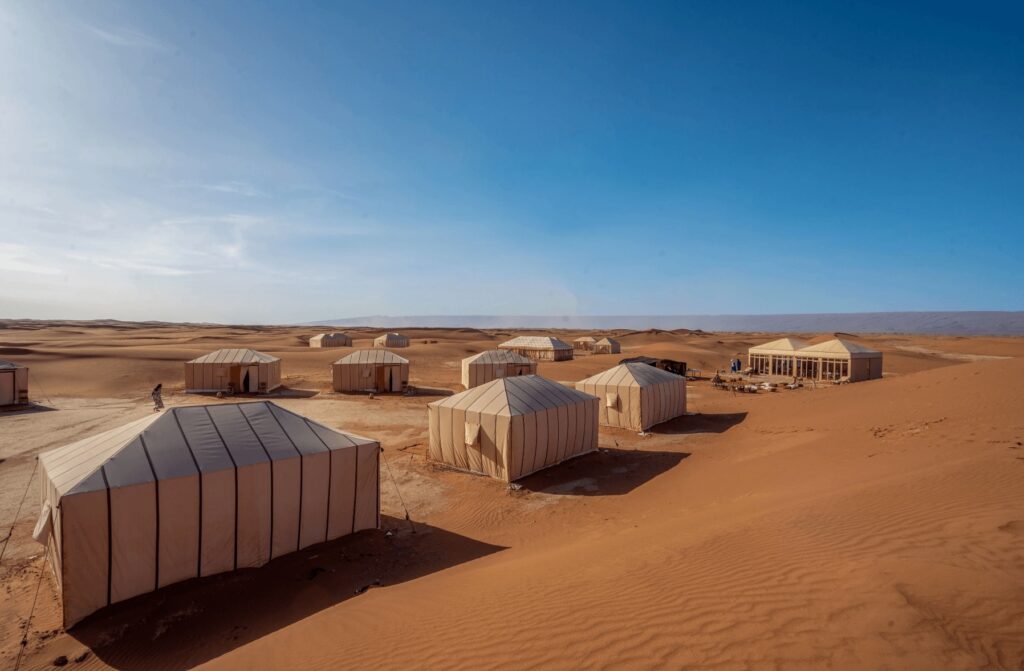Tents nestle at the base of a dune at the Erg Chigaga Desert Luxury Camp