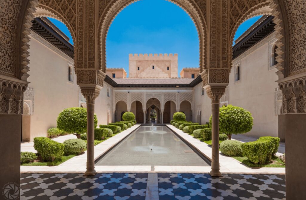 Arches frame a reflecting pool at Ksar Char Bagh, a hotel with a fireplace in the Marrakech Palmeraie