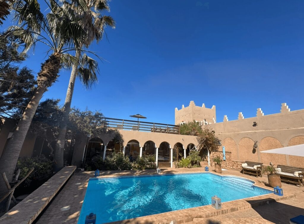 Palm trees frame a swimming pool at one of the best places to stay in Mirleft