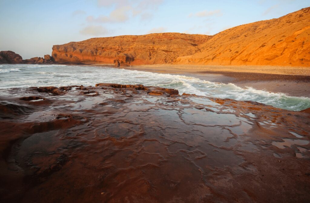 Is Mirleft worth visiting? Ochre coloured cliffs frame a beach near Mirleft
