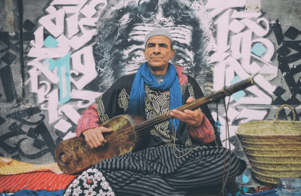 Best music festivals in MoroccoA Gnawa musician in front of a wall mural in Morocco