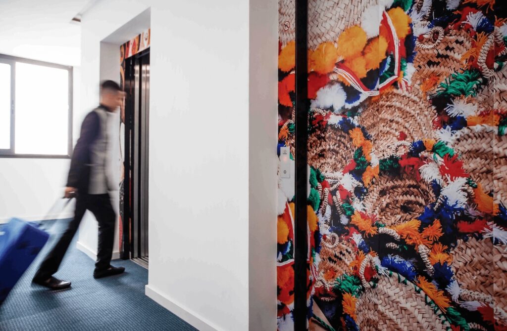 Colourful wallpaper decorates a wall beside the elevator at Relax Hotel Casa Voyageurs