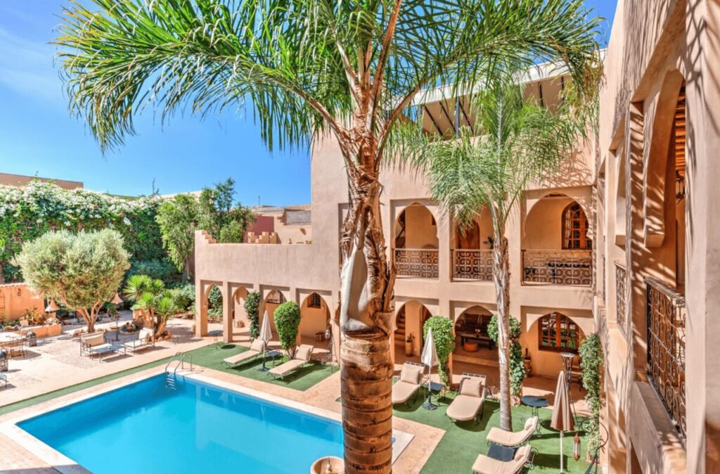 Palm trees frame a swimming pool at Riad Janoub, one of the best places to stay in Tiznit