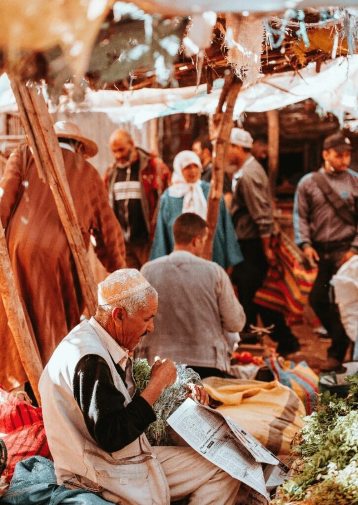 A Moroccan man folds herbs in newspaper at a local market